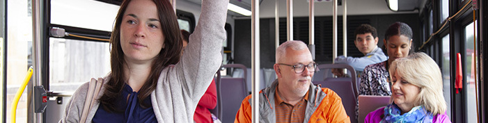 woman standing on bus while passengers talk in background